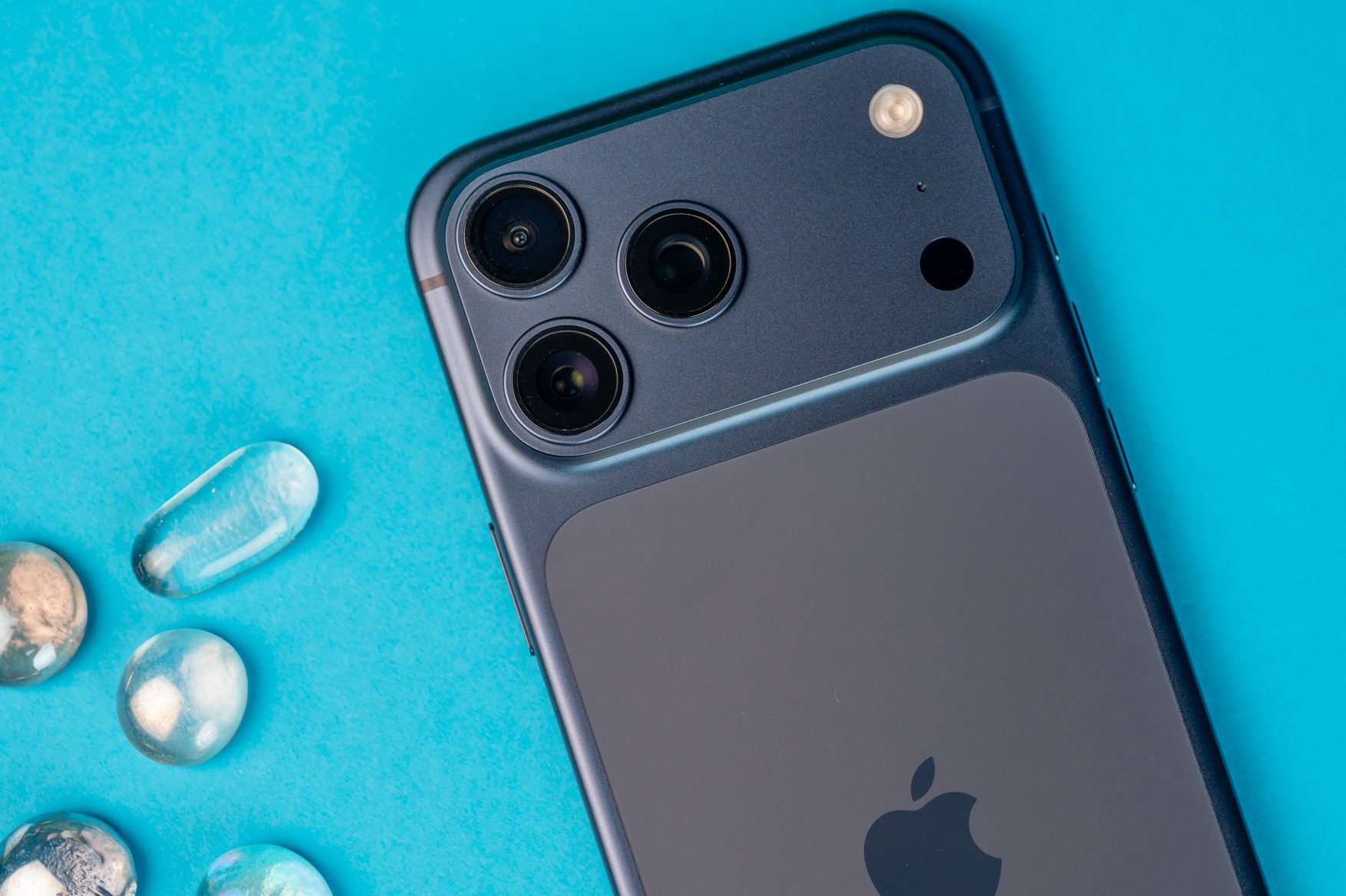 آیفون ۱۷ پرو مکس / iPhone 17 Pro Max در کنار قطرات آب پس زمینه آبی